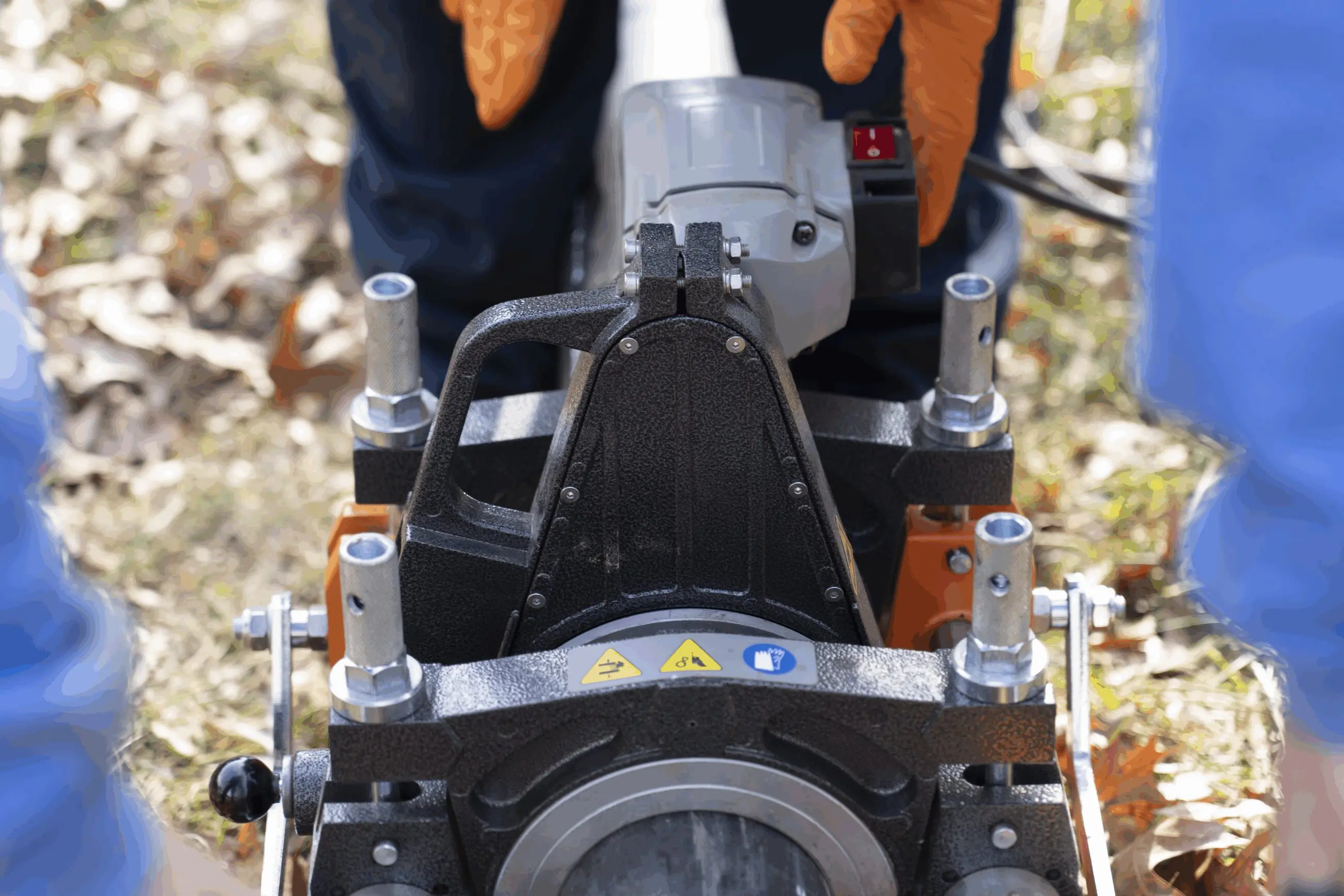 Pipe Bursting Walker-7 Technician operating a portable fusion machine on a grassy yard to join underground water or sewer pipe sections, gloved hands visible and plumbing service context for trenchless repairs and replacements.
